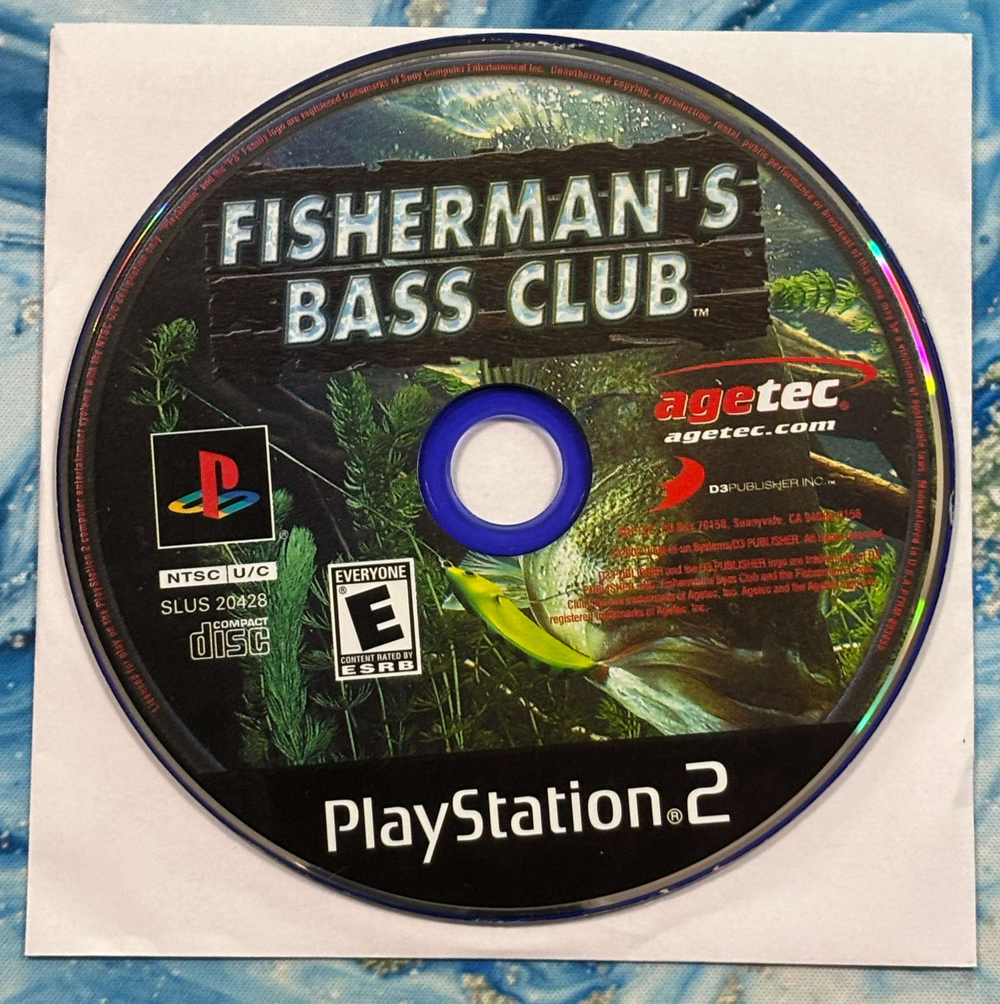 PlayStation 2 game disc for 'Fisherman's Bass Club' on a textured surface