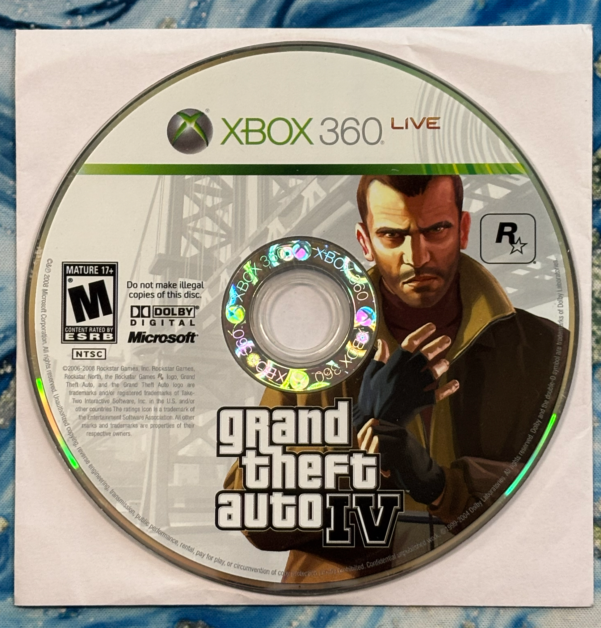 Grand Theft Auto IV Xbox 360 game disc on a textured surface