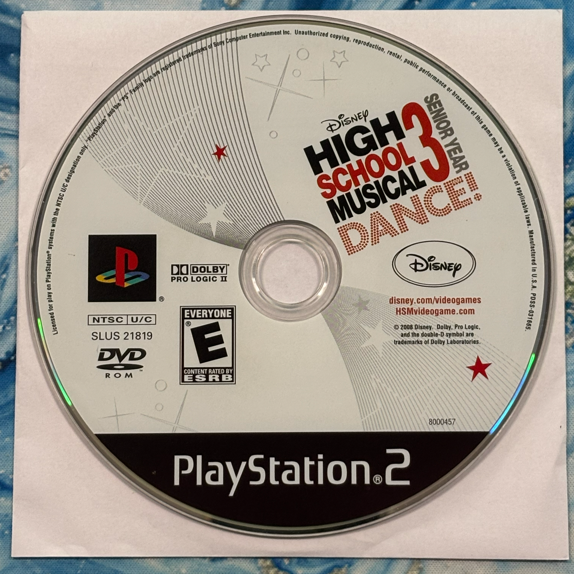 PlayStation 2 game disc for 'High School Musical 3: Senior Year Dance' on a textured surface.