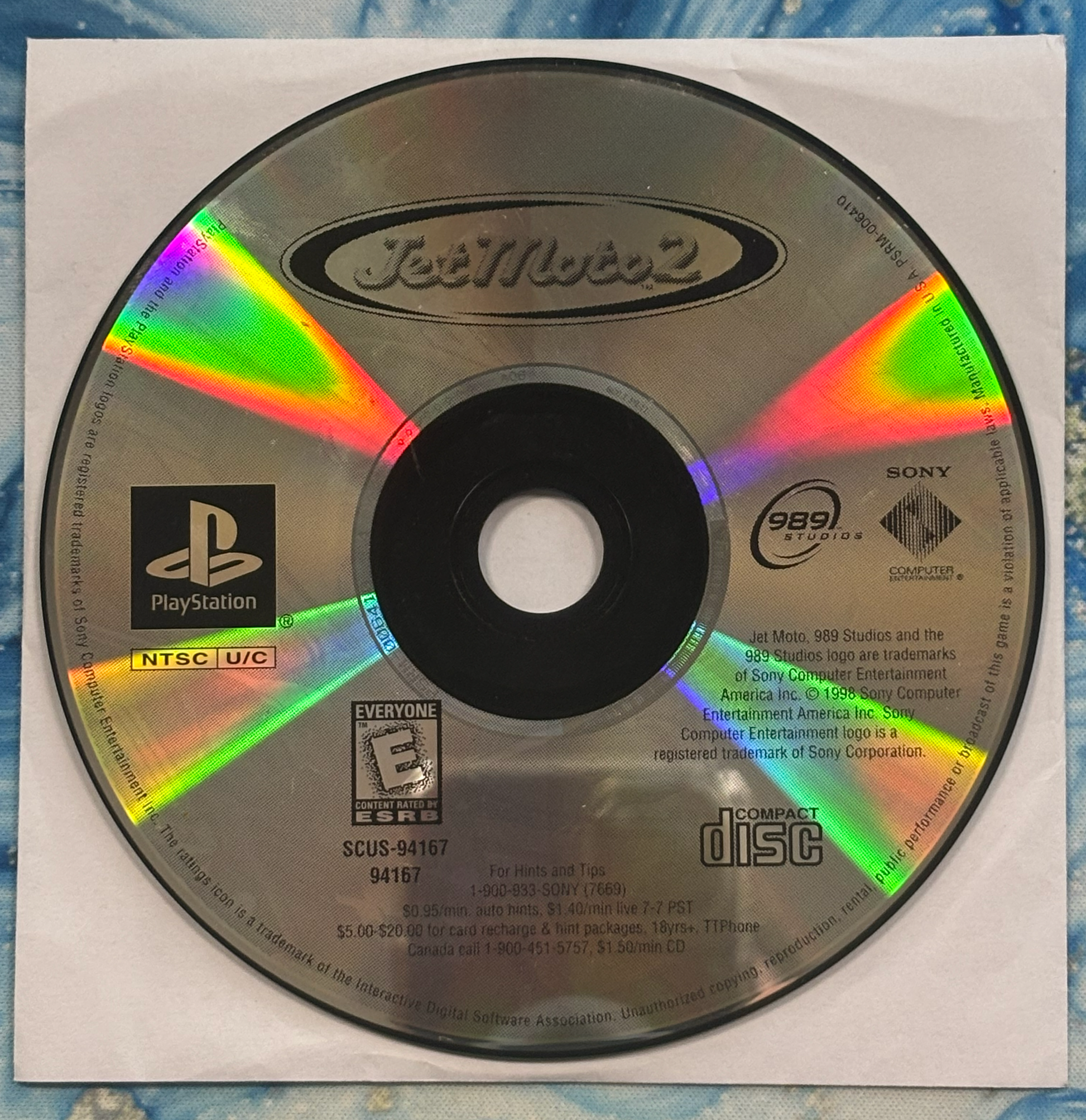 PlayStation game disc with colorful edge and visible branding on a textured surface