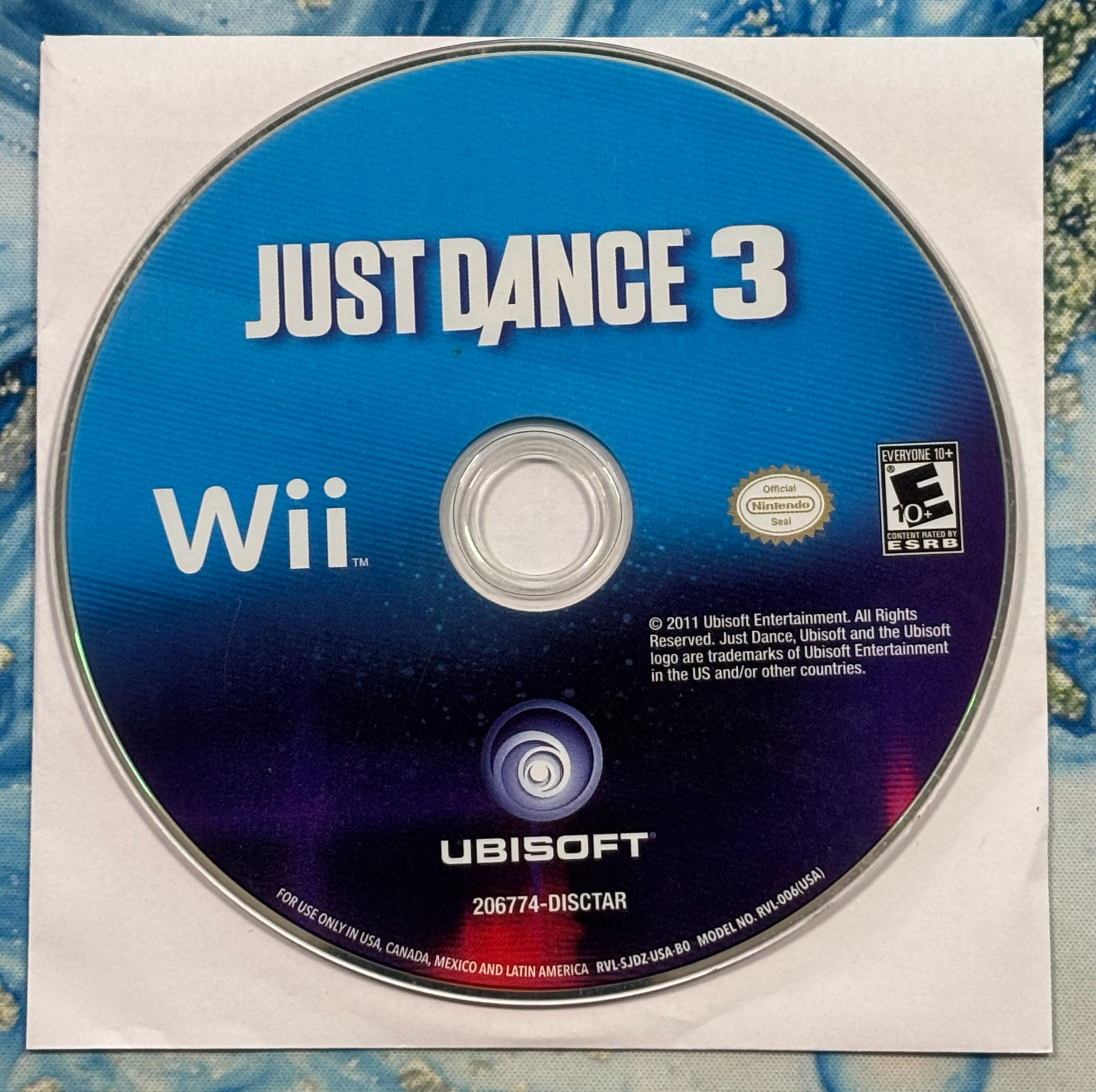 Just Dance 3 Wii game disc with Ubisoft logo on a textured surface