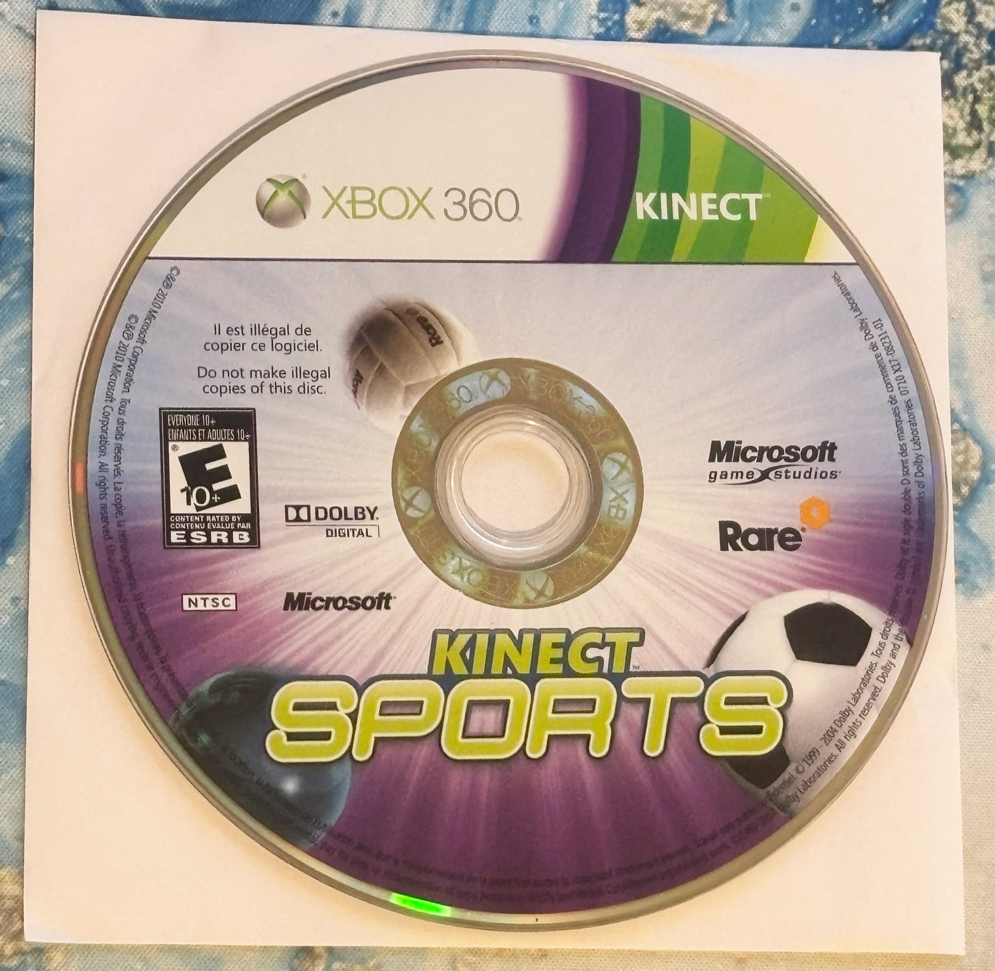 Xbox 360 Kinect Sports disc with Microsoft and Rare logos on a textured surface