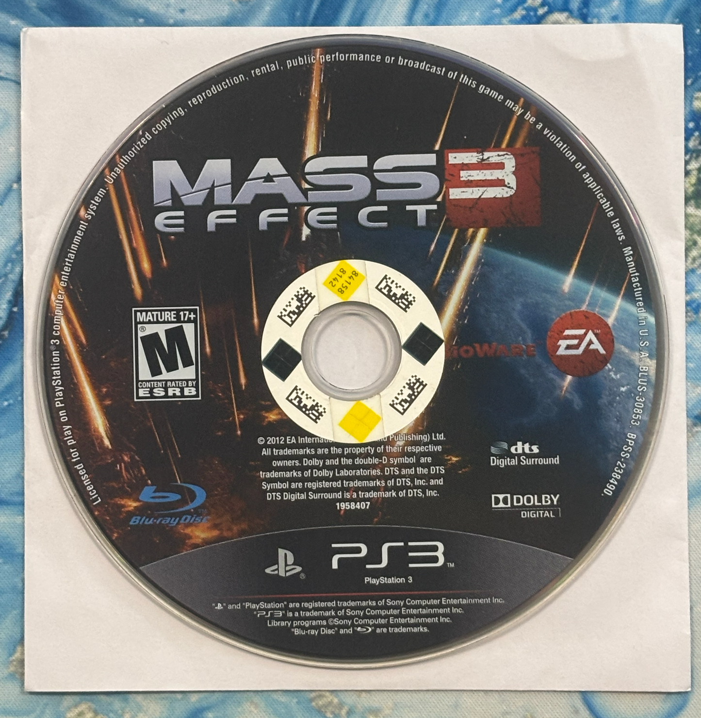 Mass Effect 3 game disc for PlayStation 3 on a textured surface
