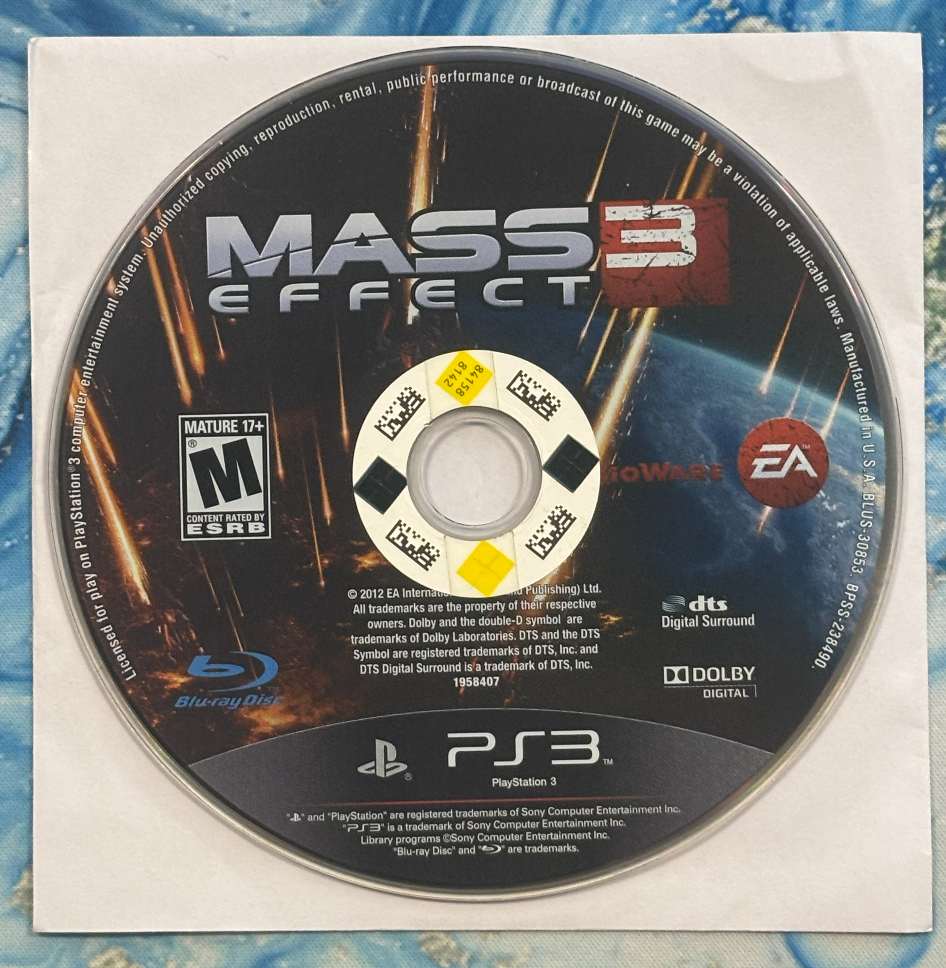 Mass Effect 3 game disc for PlayStation 3 on a textured surface