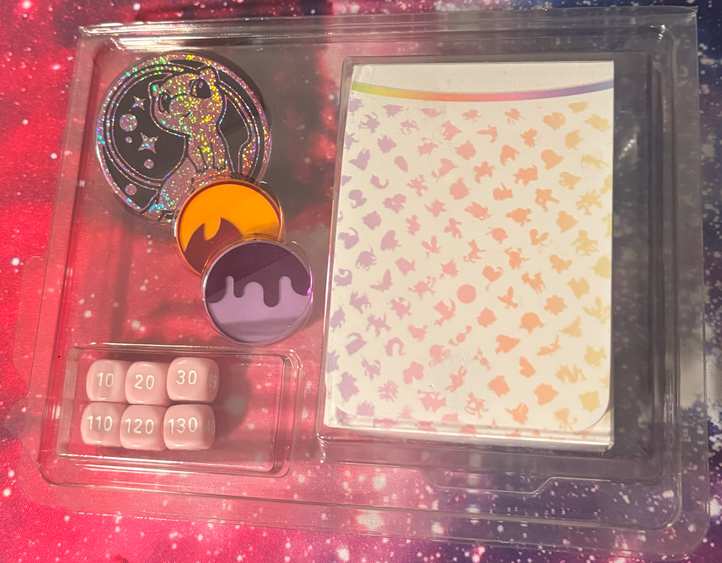 Set of dice and gaming accessories in a clear plastic case with a colorful background