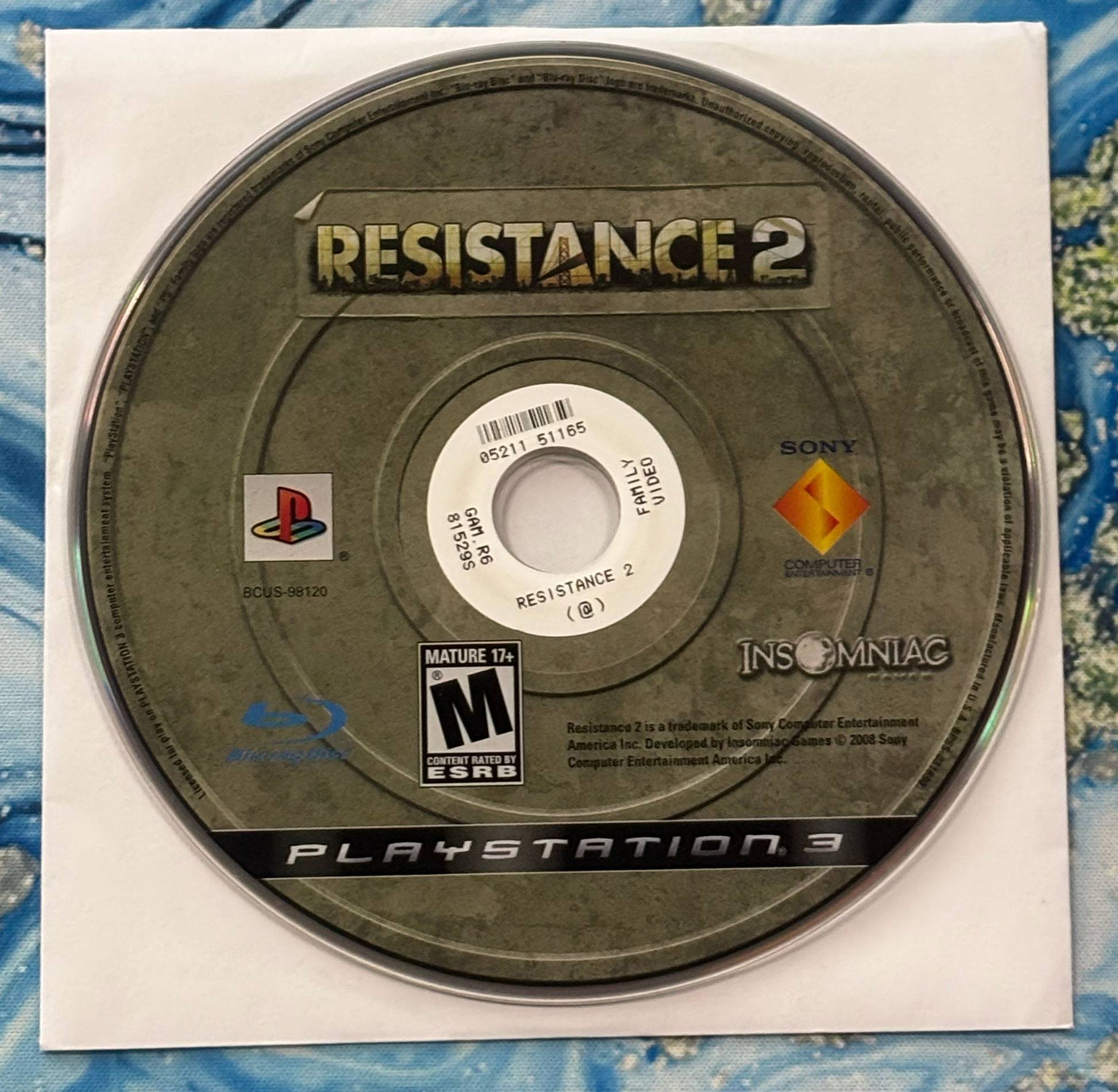 Game disc for 'Resistance 2' on a PlayStation 3 console with branding and logos.