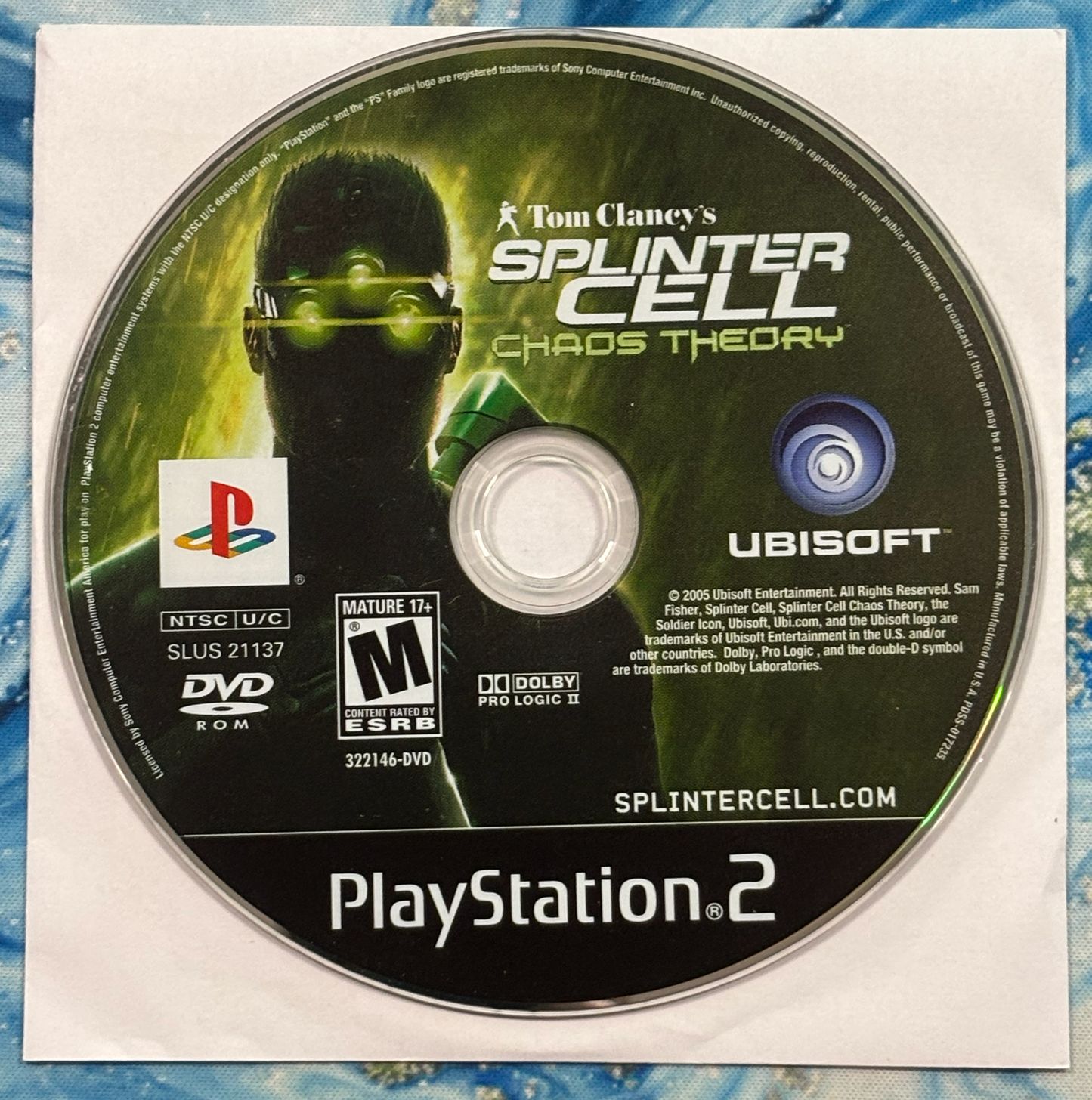 Tom Clancy's Splinter Cell Chaos Theory PlayStation 2 game disc on a textured surface