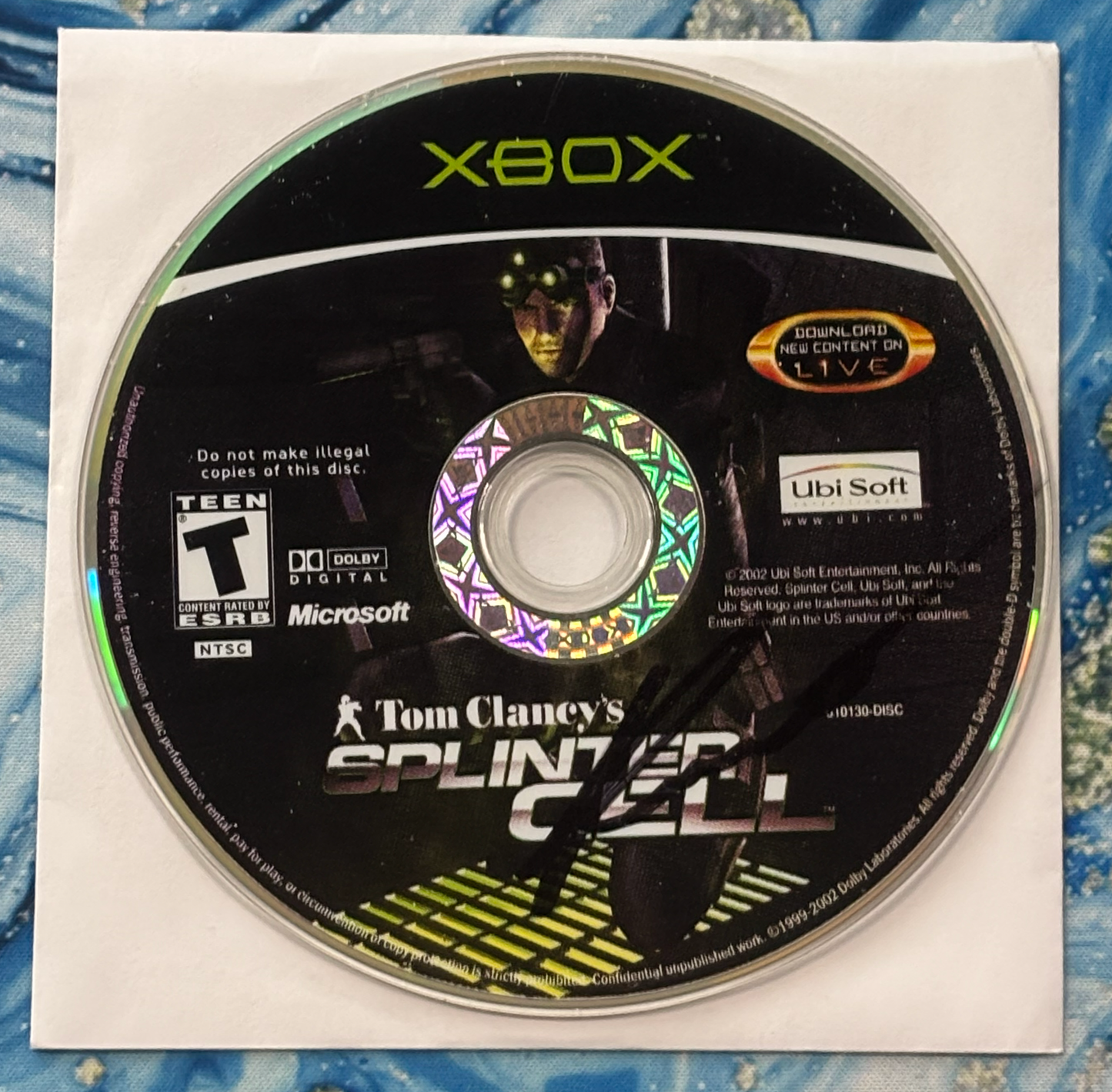 Xbox game disc for 'Tom Clancy's Splinter Cell' on a textured surface