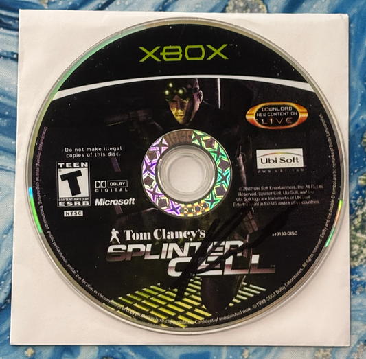 Xbox game disc for 'Tom Clancy's Splinter Cell' on a textured surface